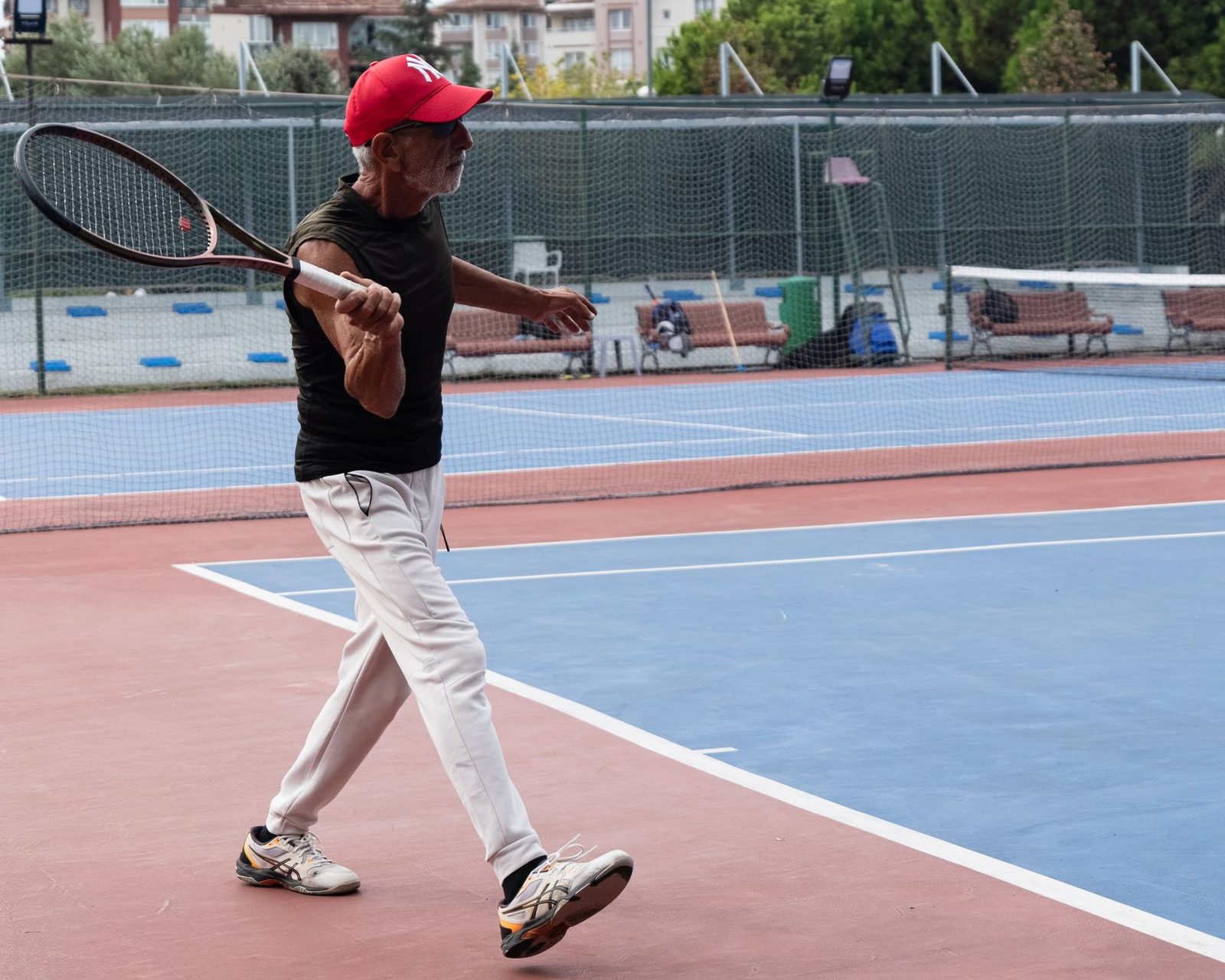 An older man playing tennis on a sunny outdoor court