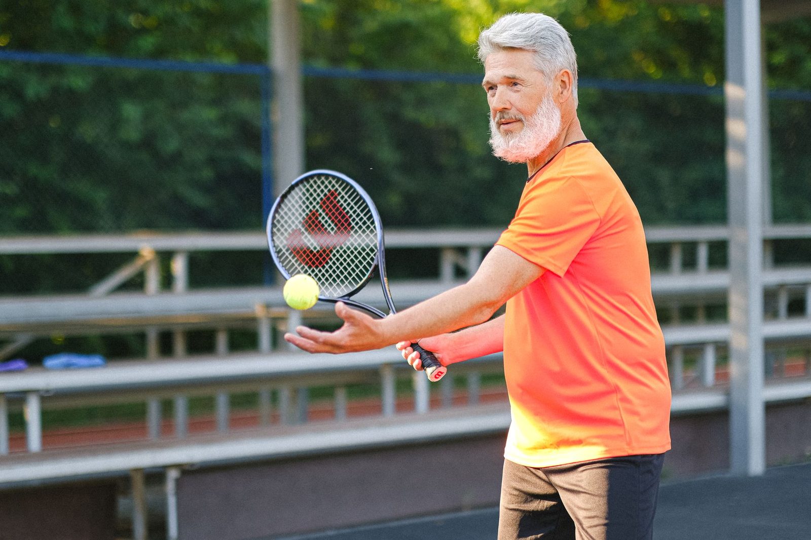 Senior player preparing to serve with ball and racquet in hand
