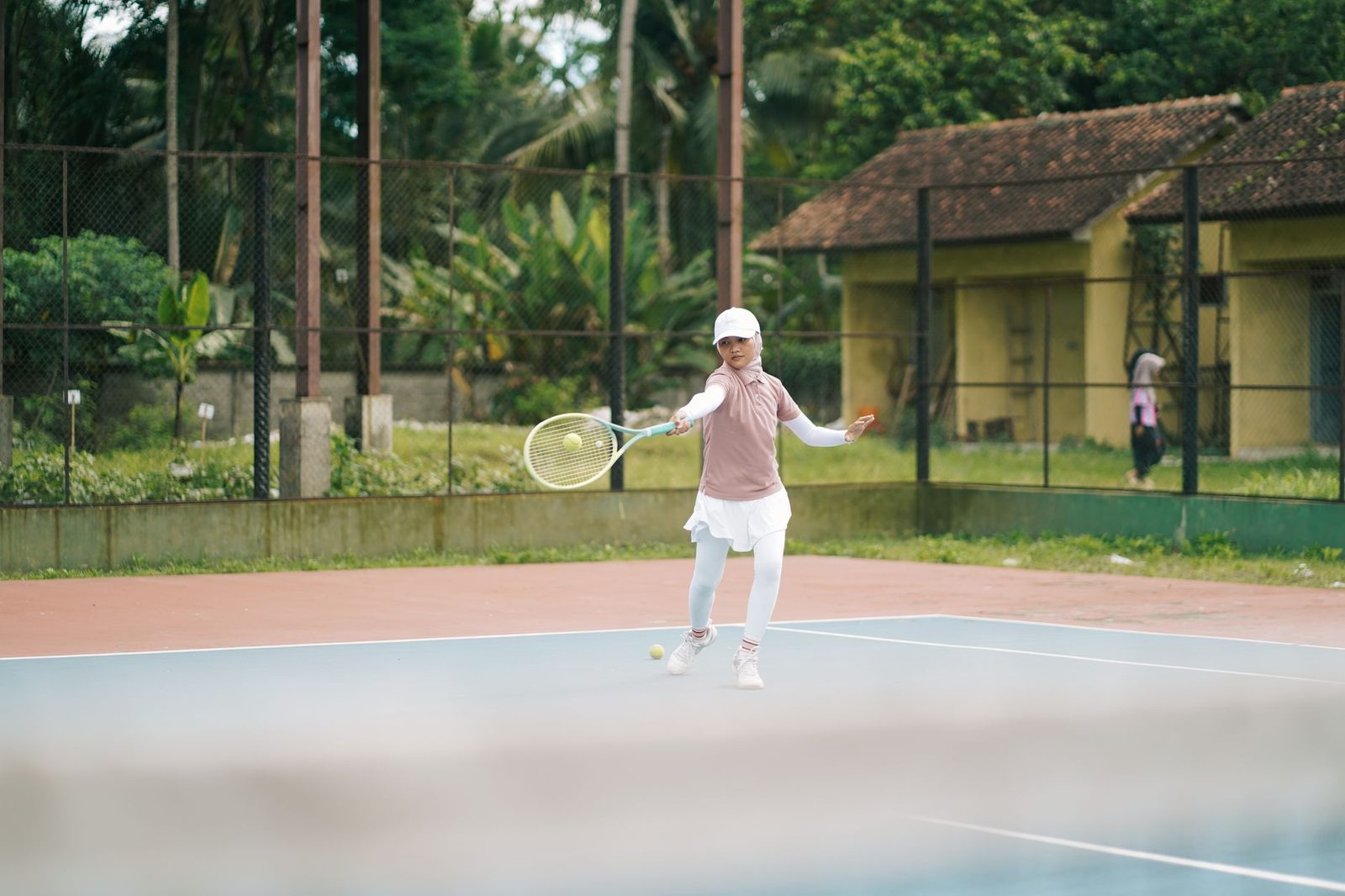 A young girl playing tennis on an outdoor court during the day