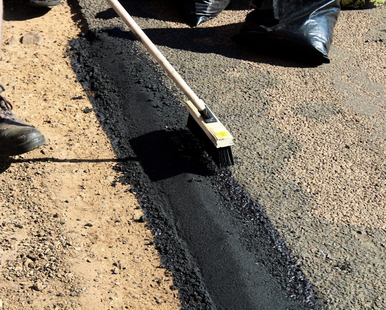 Fresh asphalt being laid and worked with hand tools during surface construction