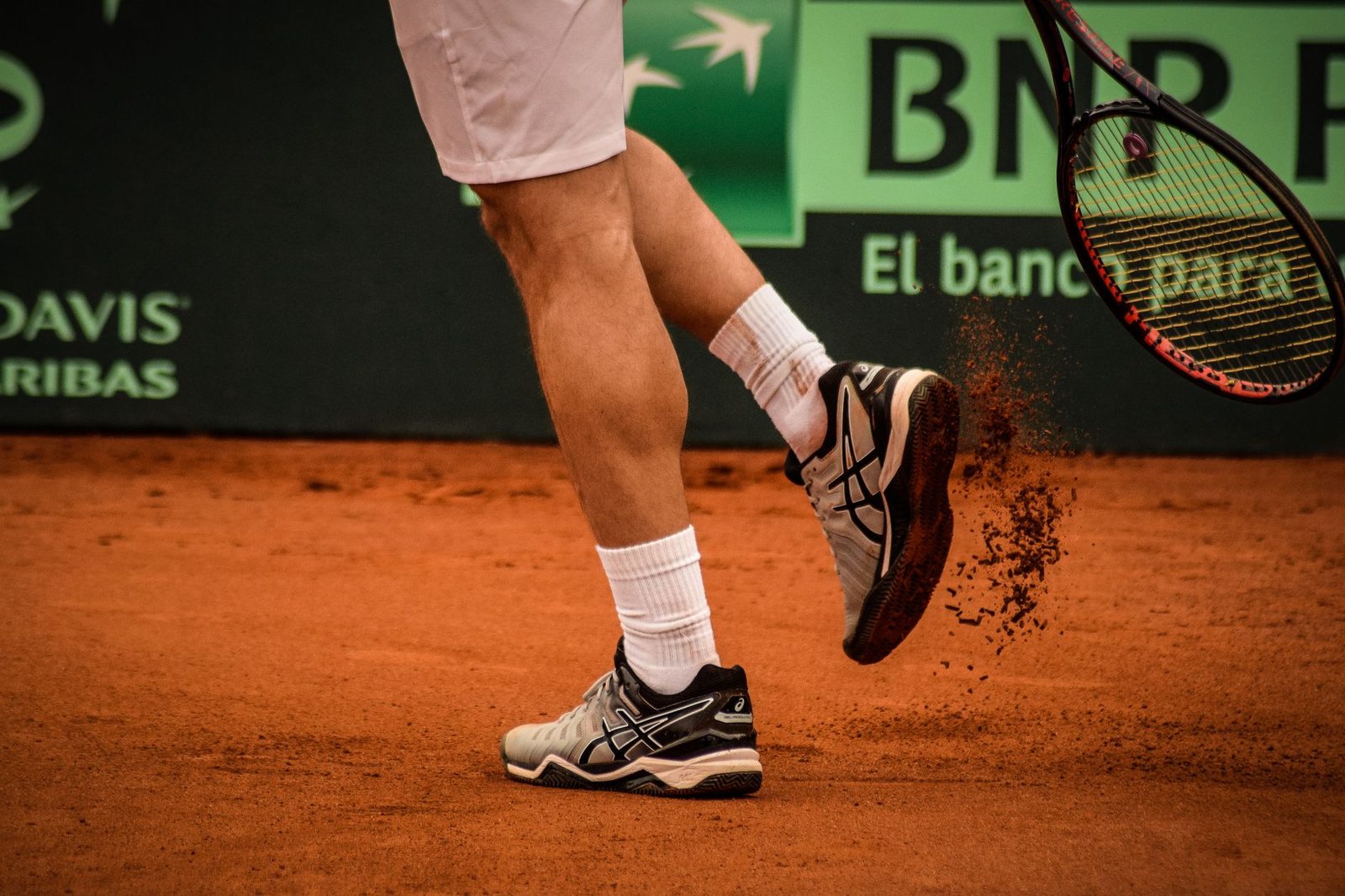 Close view of a tennis player moving on a clay court