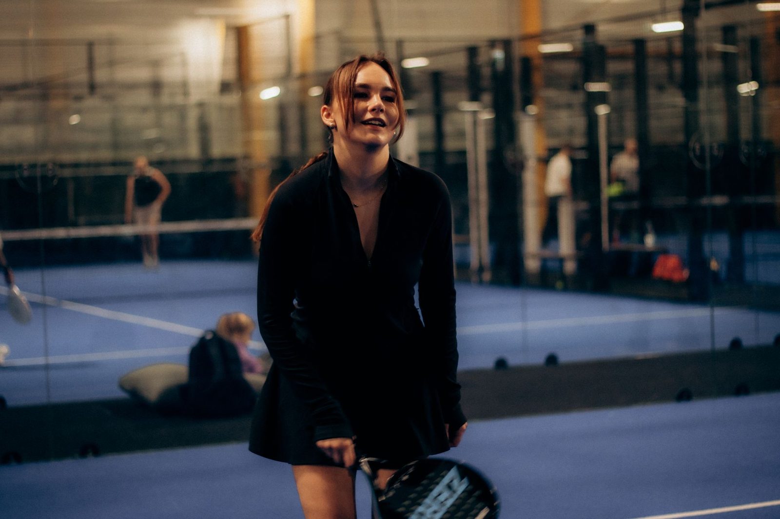 A young woman playing tennis indoors with a racquet