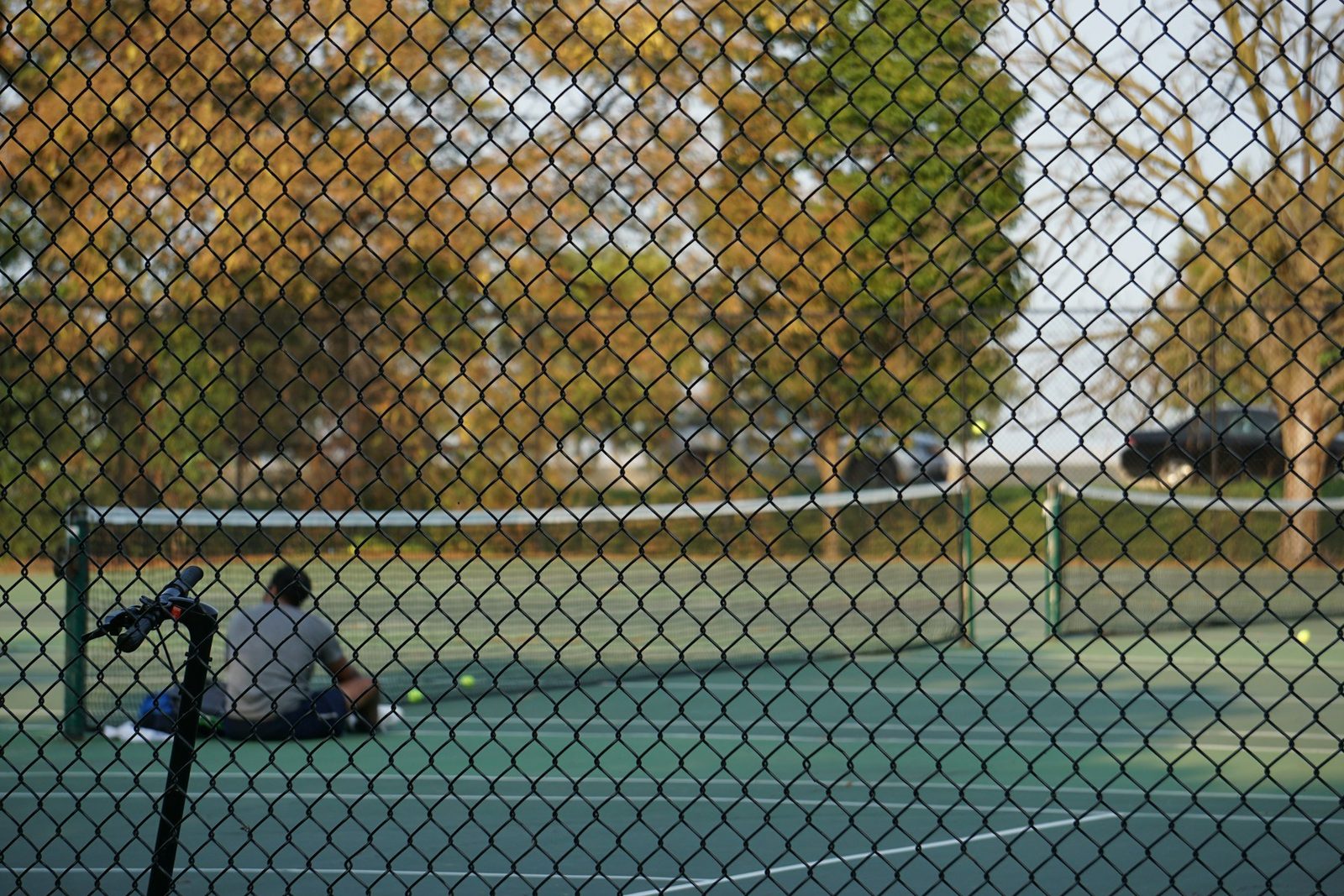 A man sitting on a tennis court with balls around him