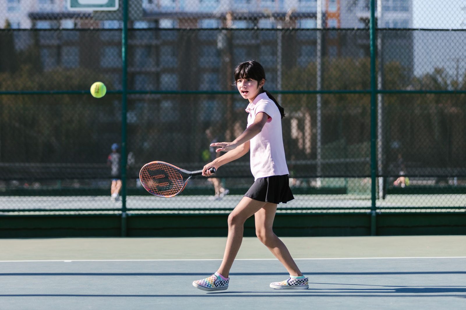 A young girl playing tennis, hitting a forehand on a sunny day
