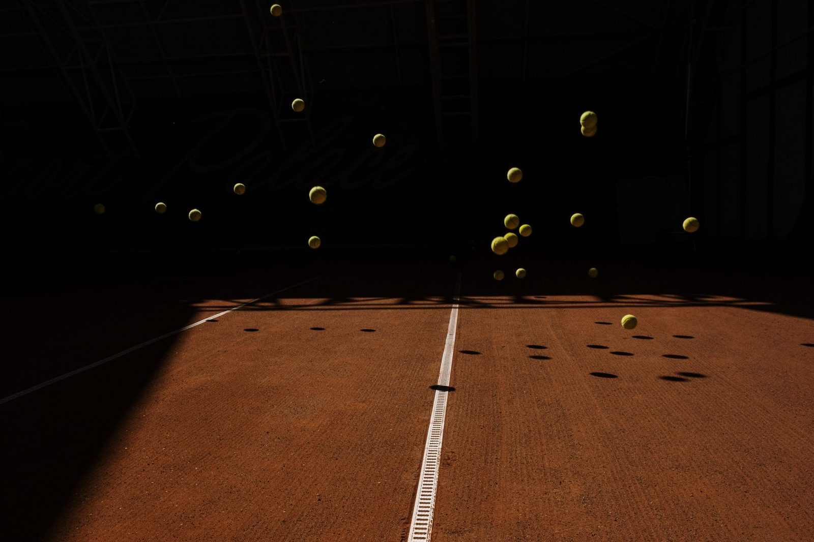 Tennis balls bouncing on an indoor court, casting shadows
