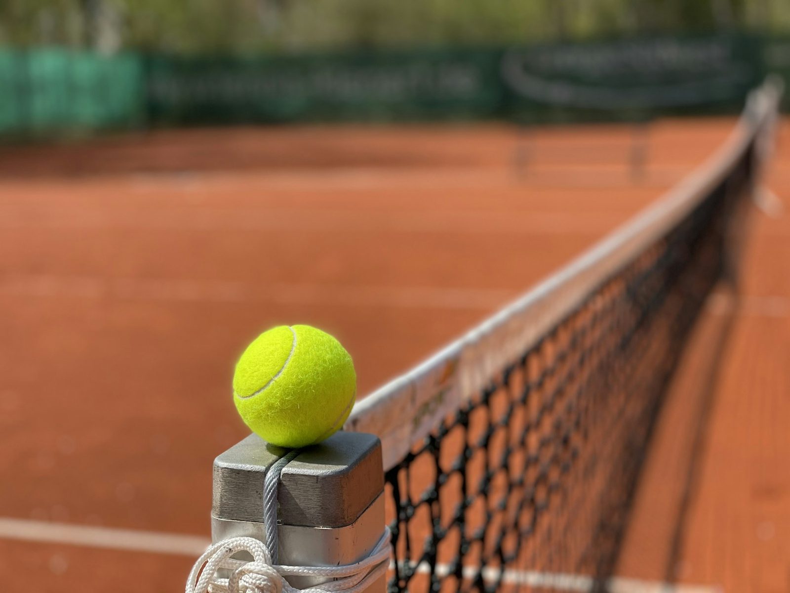 A single tennis ball resting on a court before practice