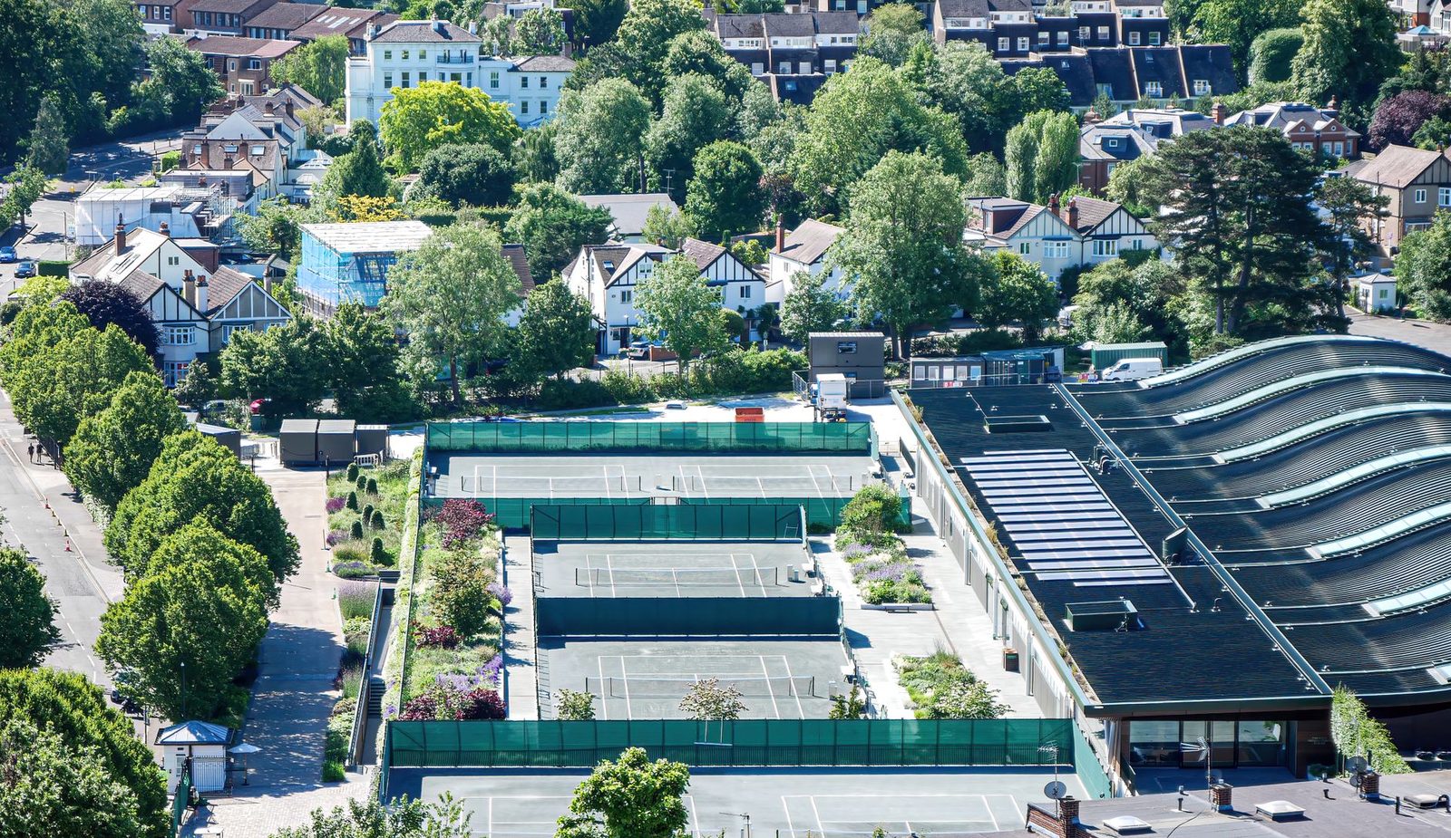 Aerial view of tennis courts set among houses and trees in a suburban neighbourhood