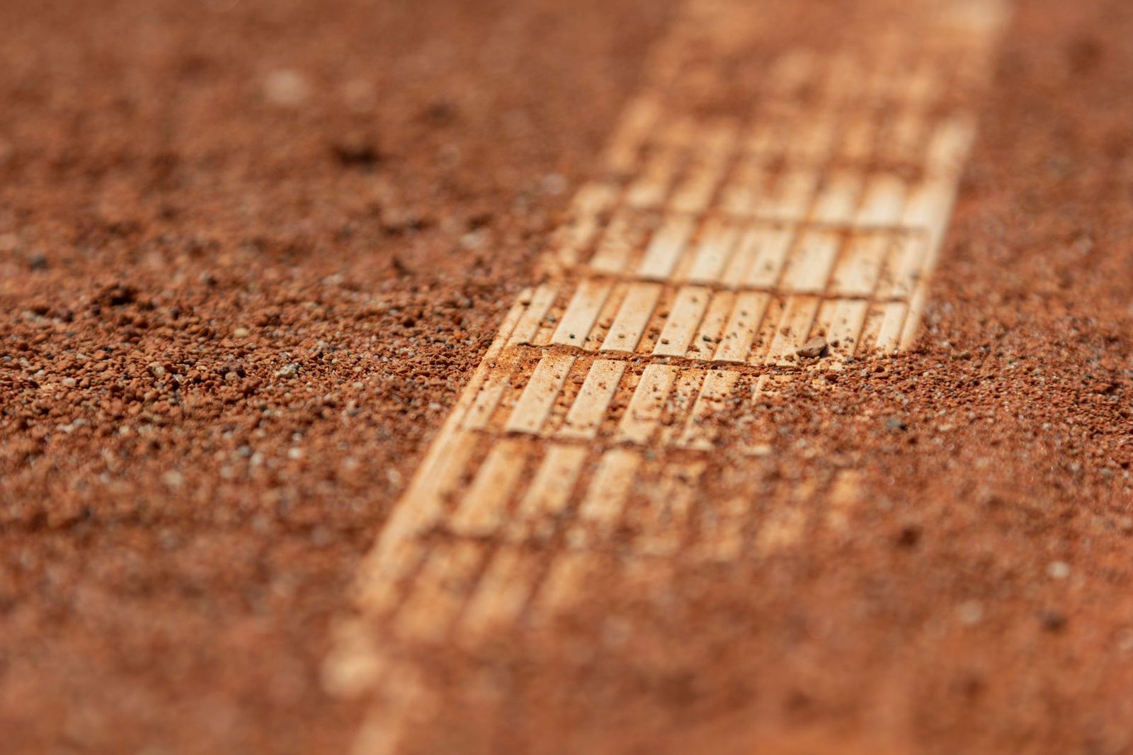 Close view of a red clay tennis court surface with court lines