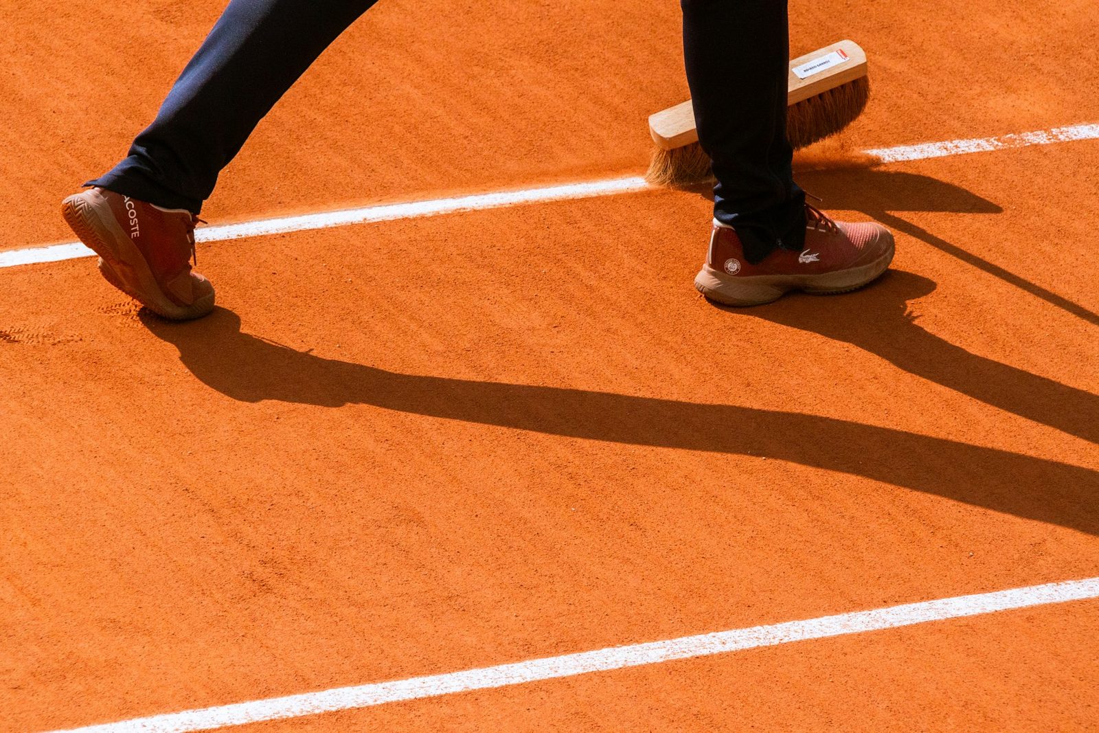 A clay tennis court being swept after play