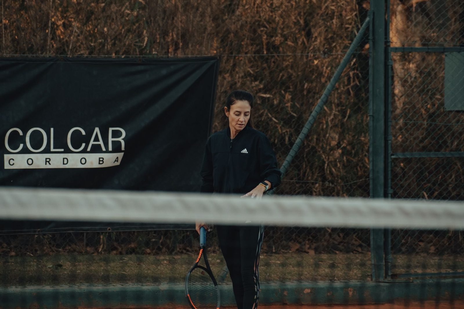 A woman holding a racquet on an outdoor clay tennis court