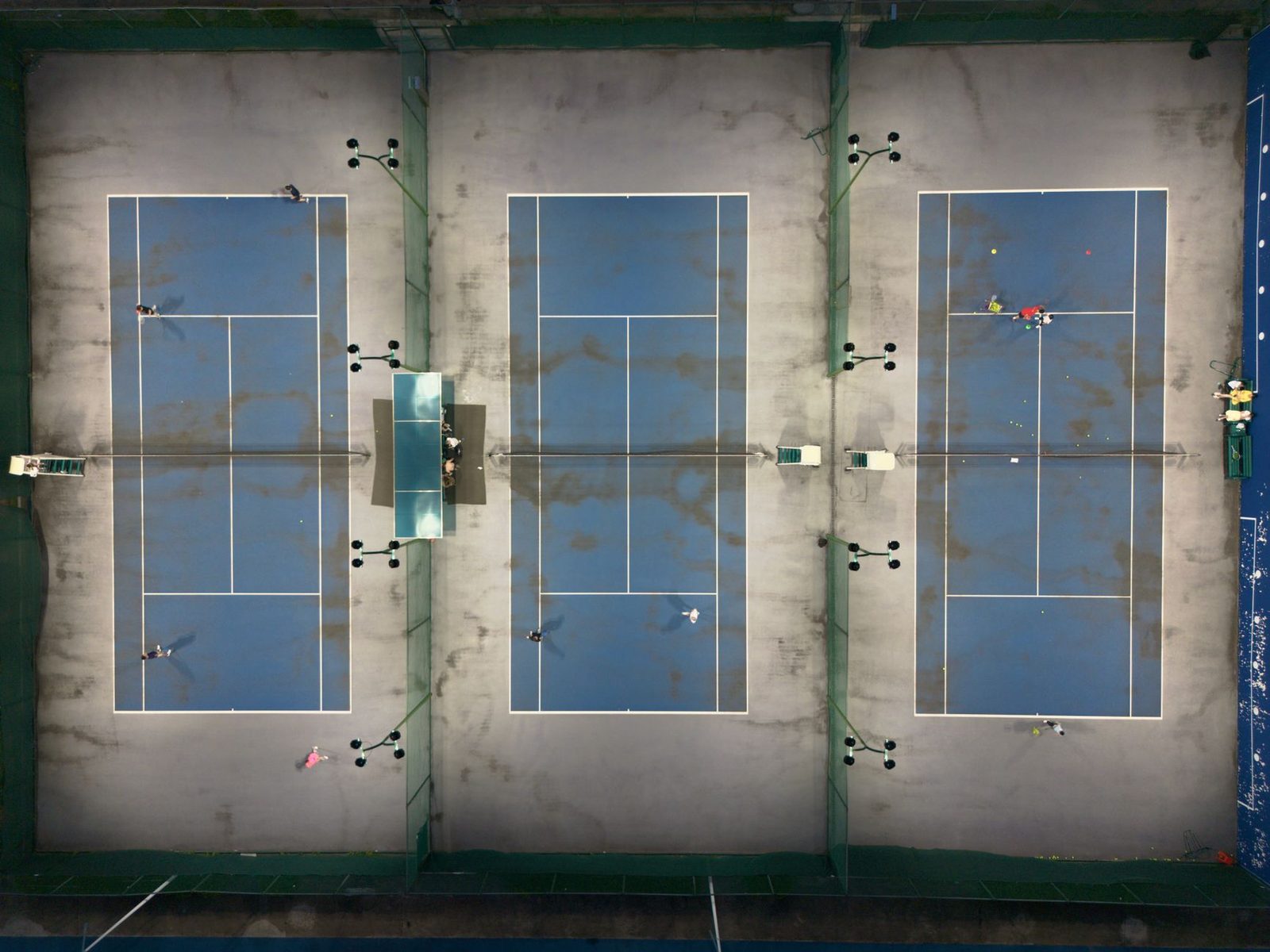 Aerial view of three tennis courts with players during the day