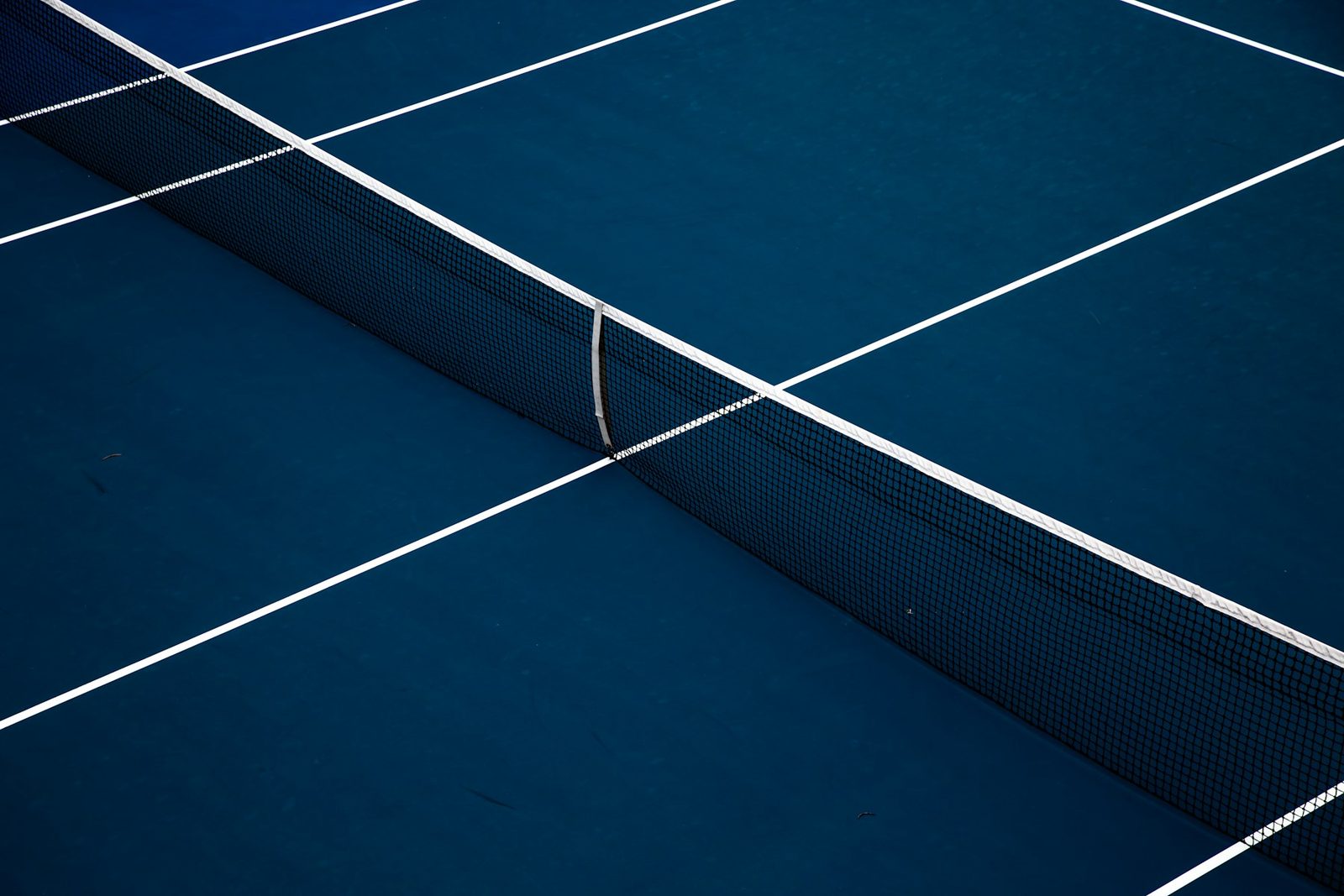 A blue tennis court with white line markings