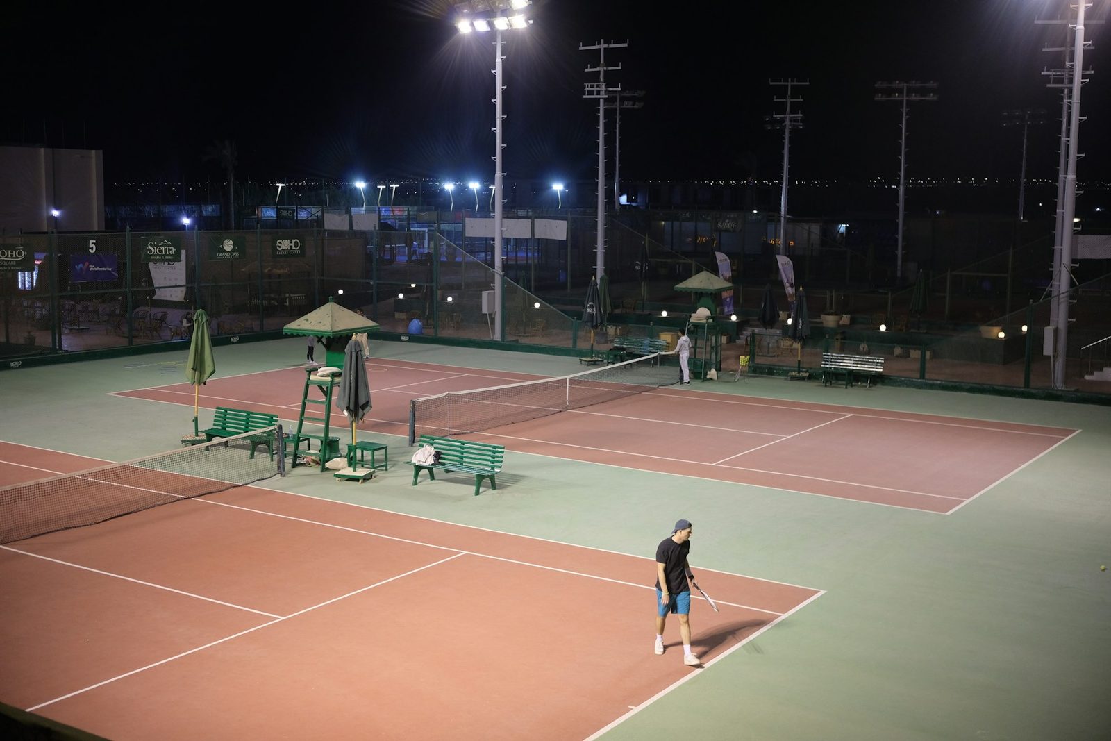 Several tennis courts lit by floodlights at night