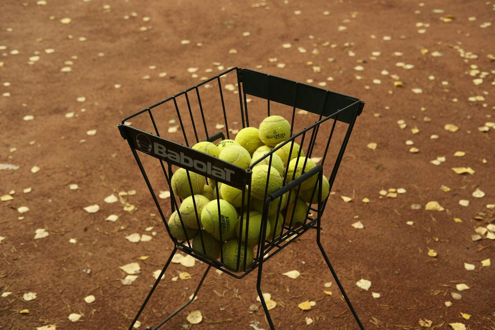 A basket of tennis balls on a metal stand