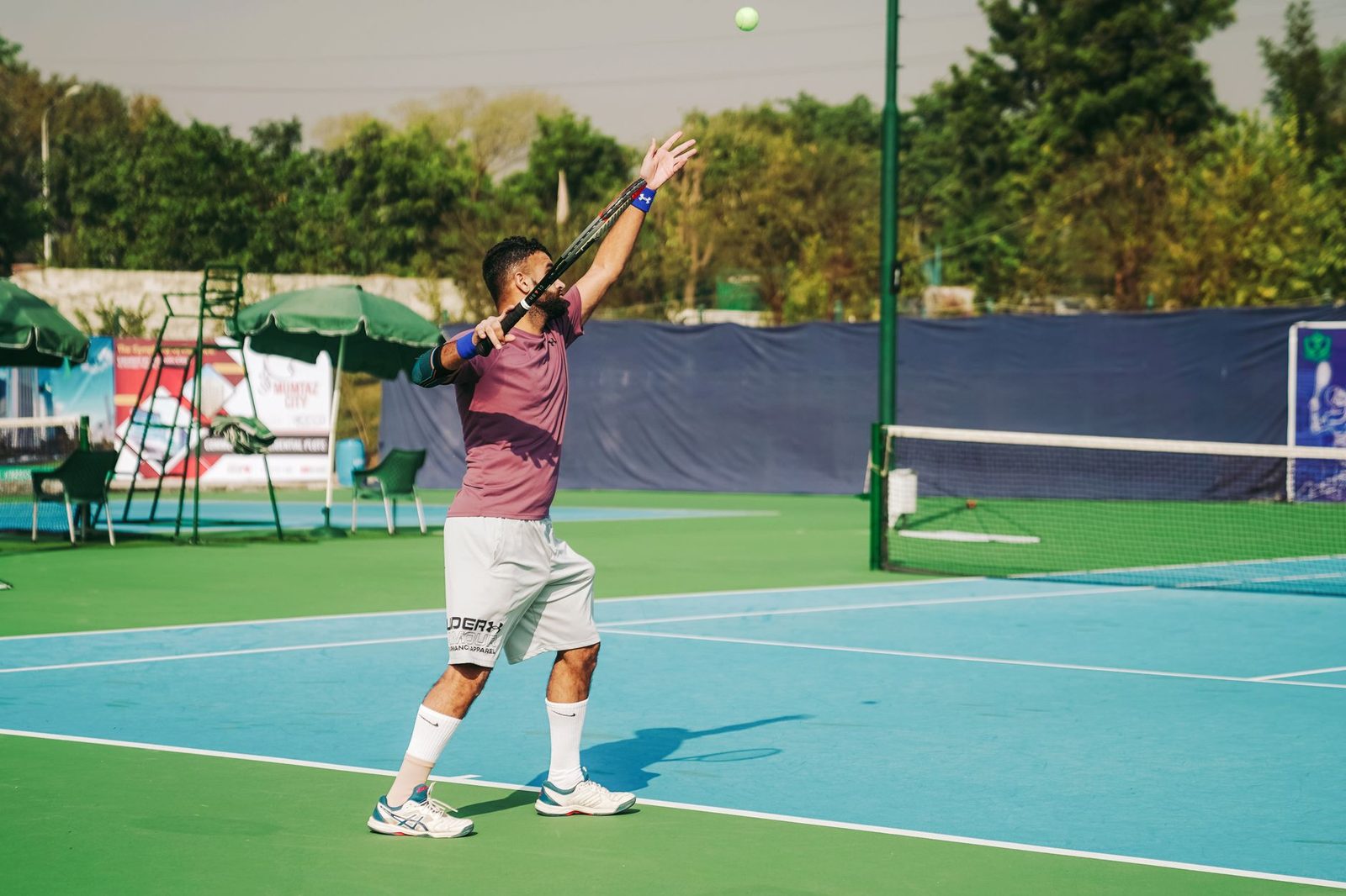 Tennis player serving on an outdoor court under clear skies