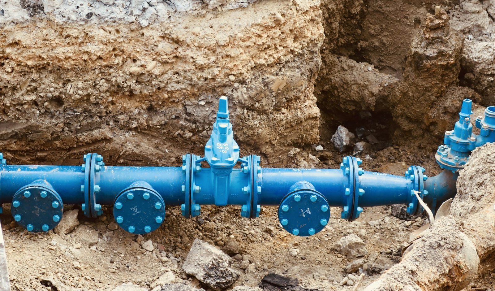 Blue drainage pipe laid on a mound of excavated soil at a building site