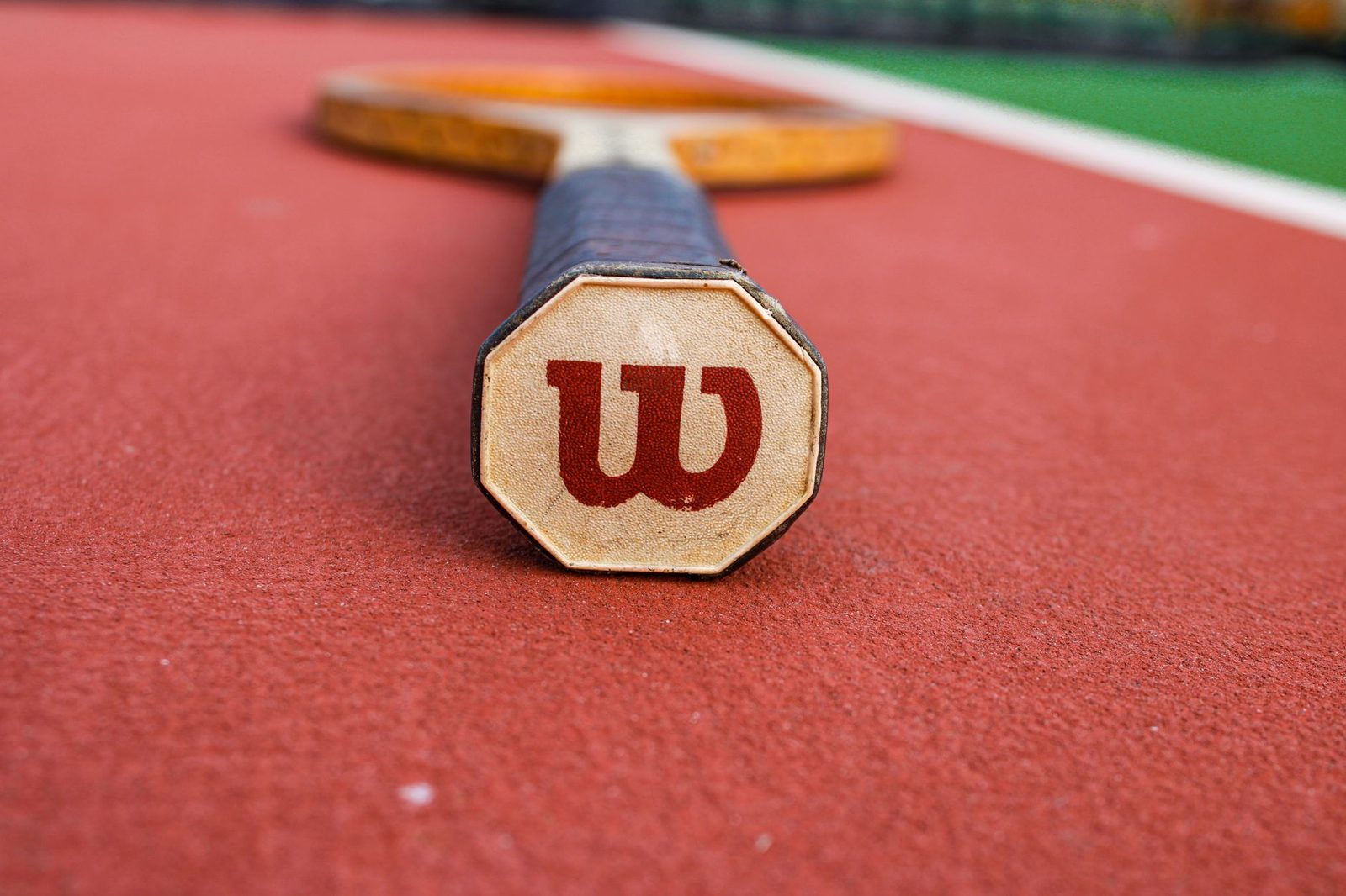 Close view of a tennis racquet on a red clay court surface