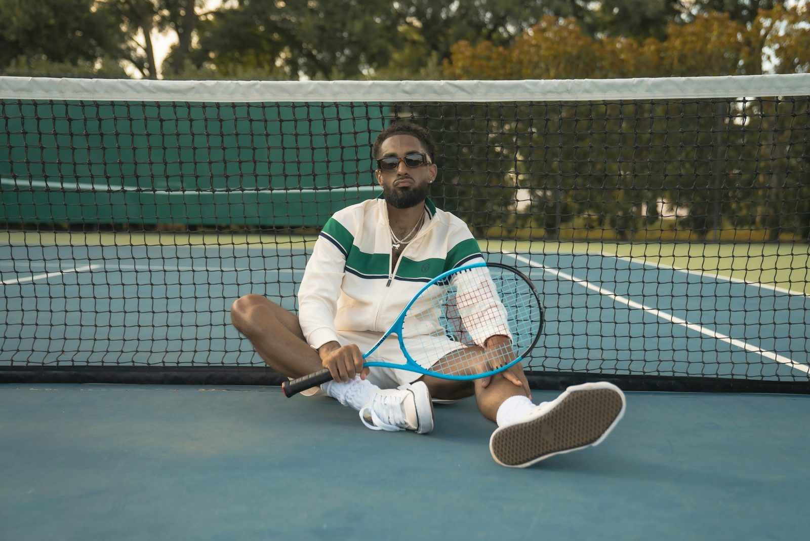 A man sitting on a tennis court holding a racquet