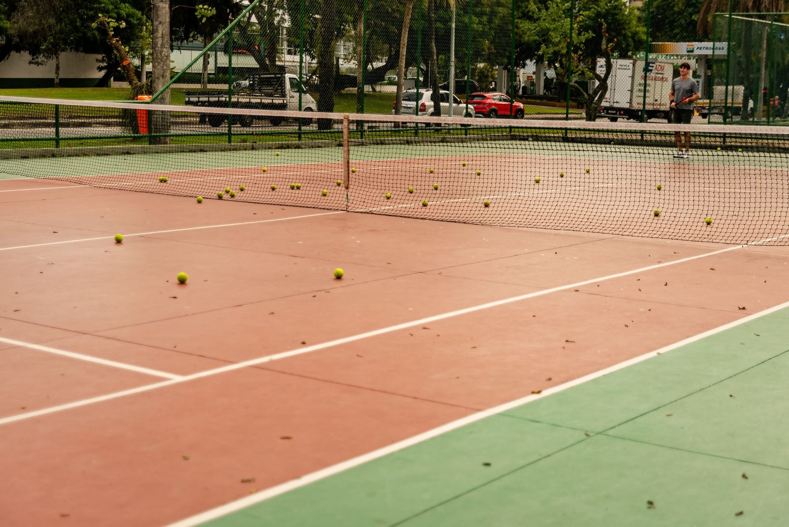 A tennis court with balls scattered across the surface