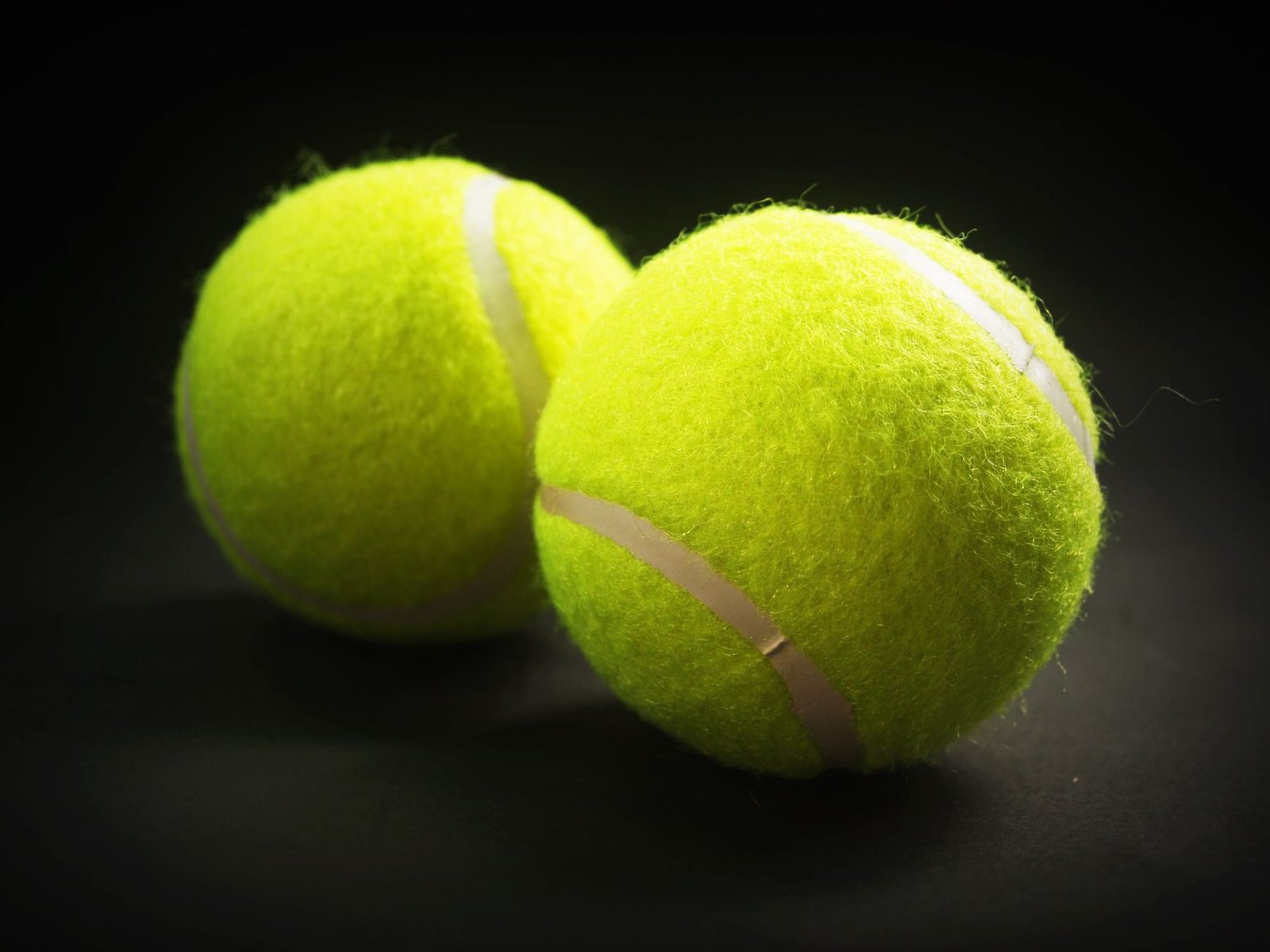 Close view of two bright yellow tennis balls