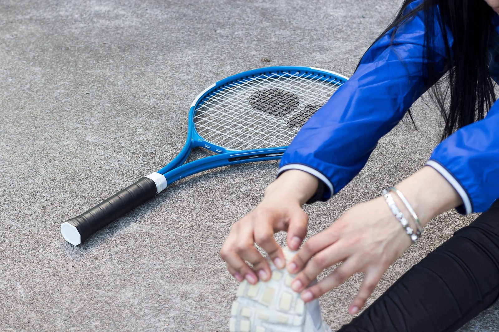 Close view of a player stretching low beside a racquet on court