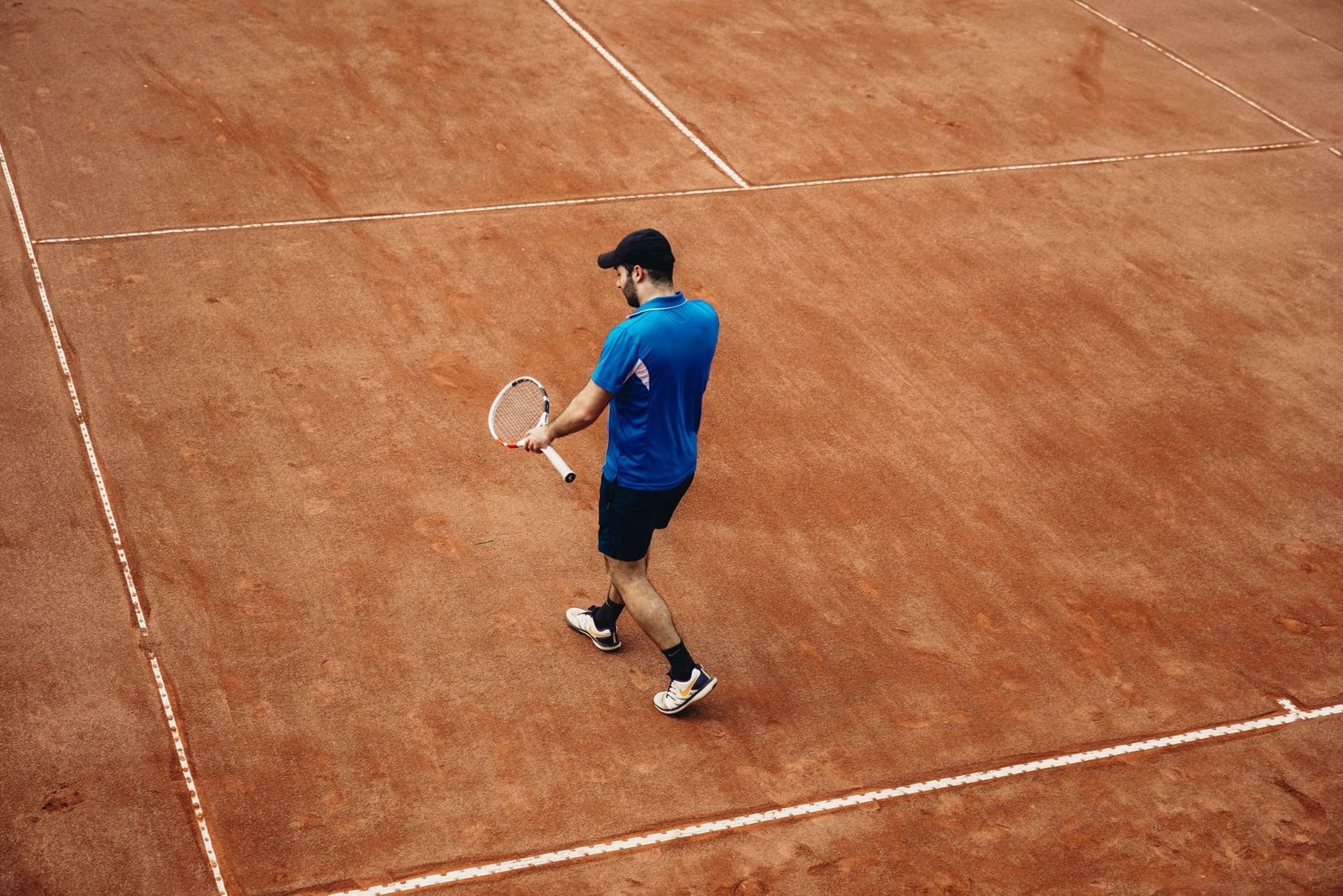 Athlete holding a tennis racquet on a clay court during summer practice