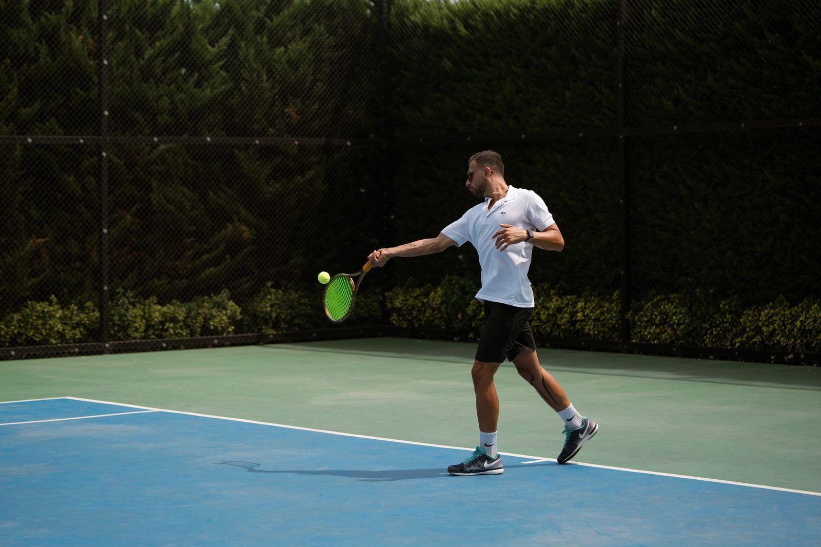 Adult player hitting a forehand outdoors on a sunny day