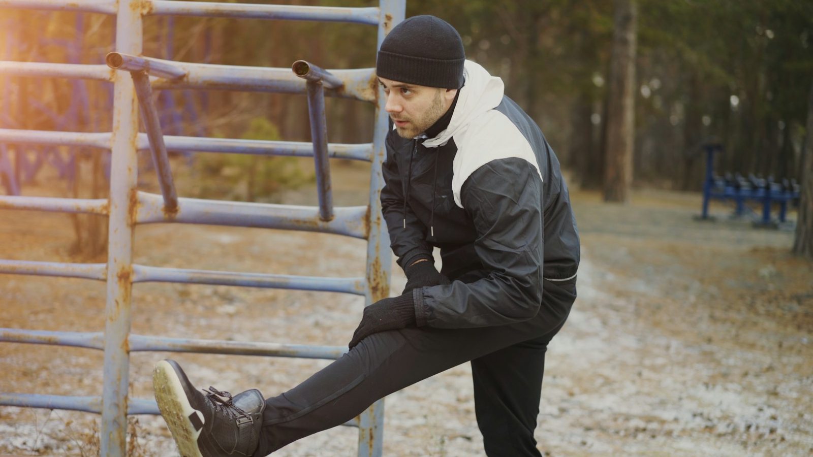 A man stretching his legs on outdoor exercise equipment