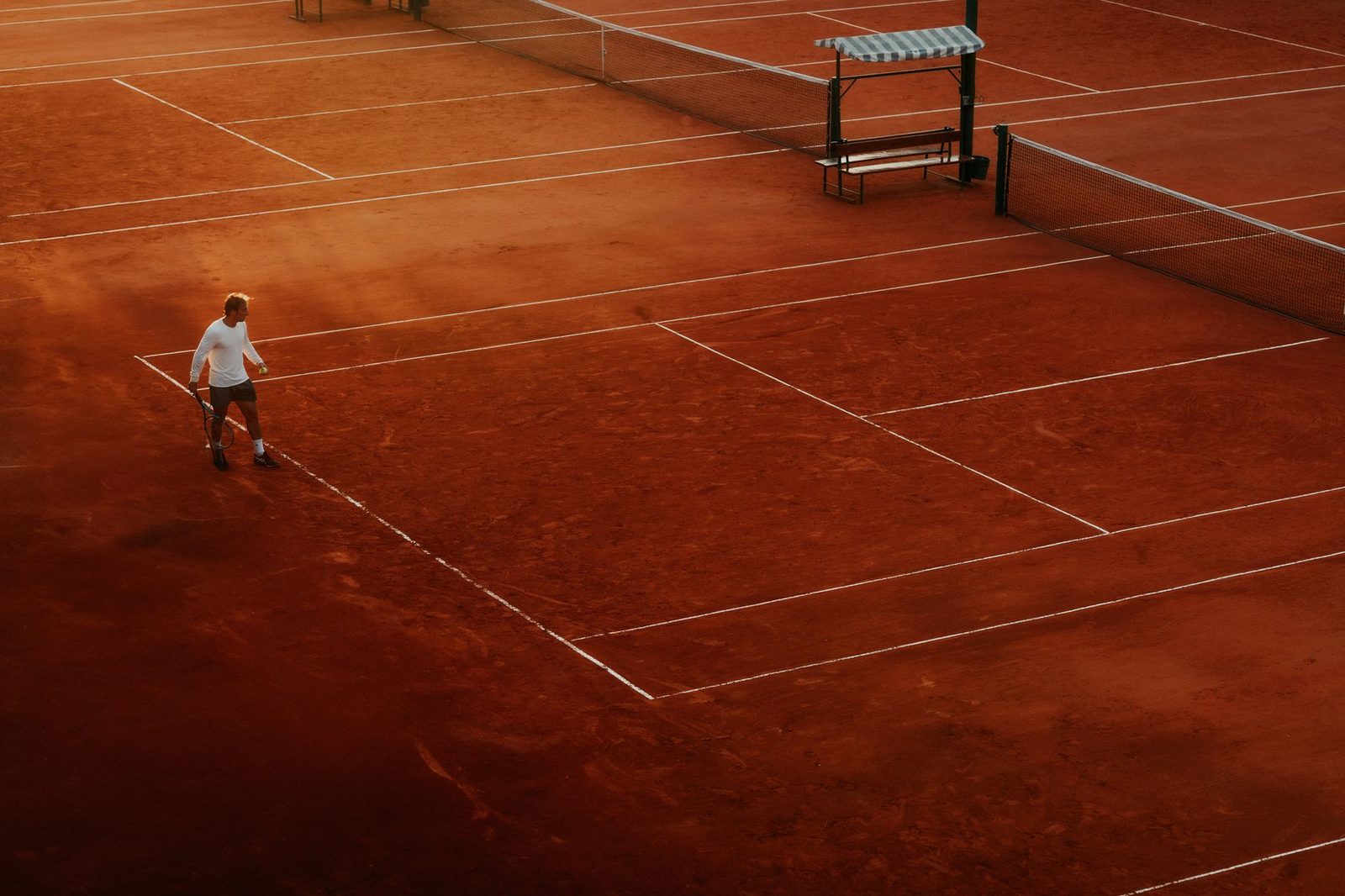Aerial view of a tennis player on a clay court during the day