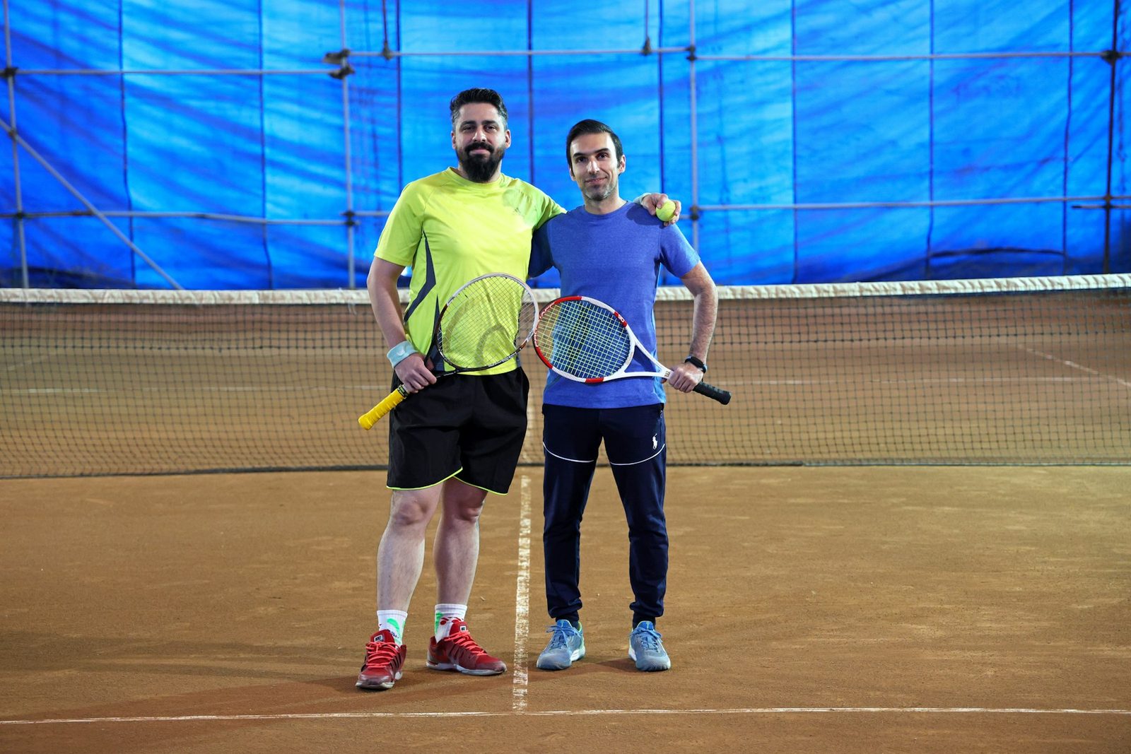 Two men holding tennis racquets on a court