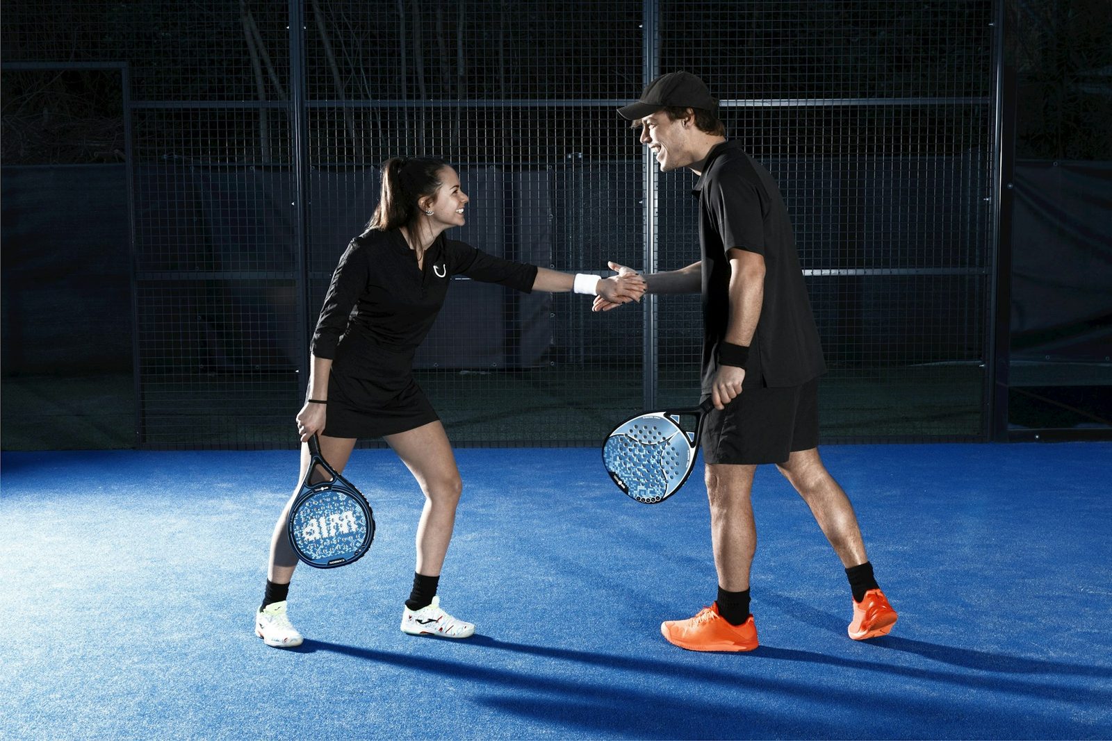 Two players shaking hands on a tennis court after a match