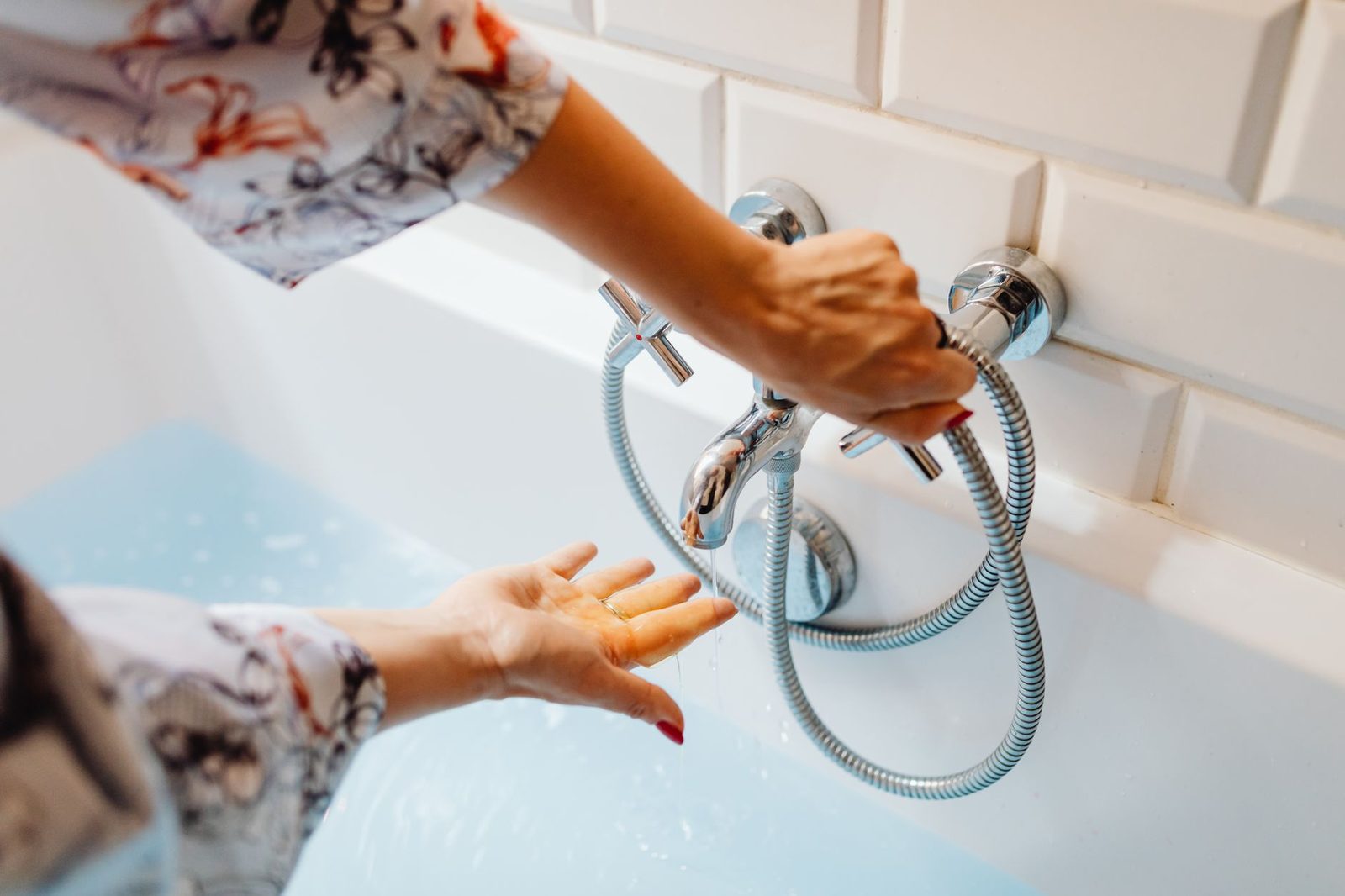 Close view of hands adjusting the water temperature at a bath tap