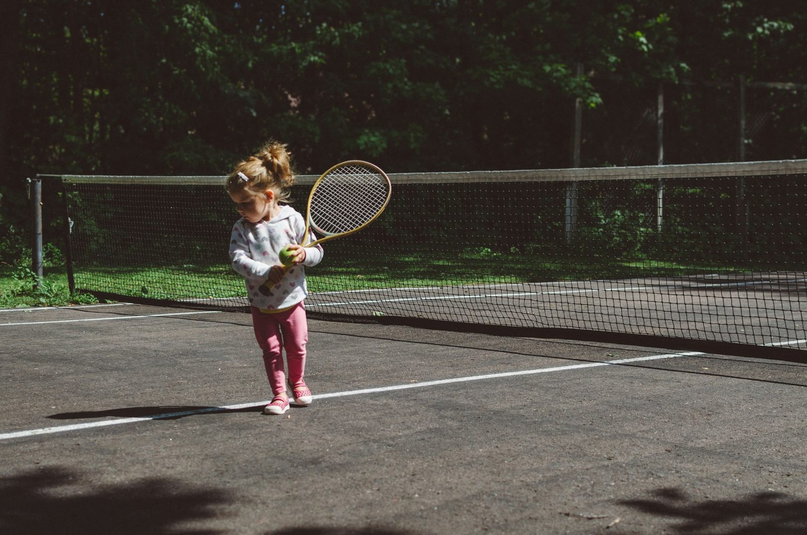 Girl holding a tennis racquet beside the net during a junior lesson
