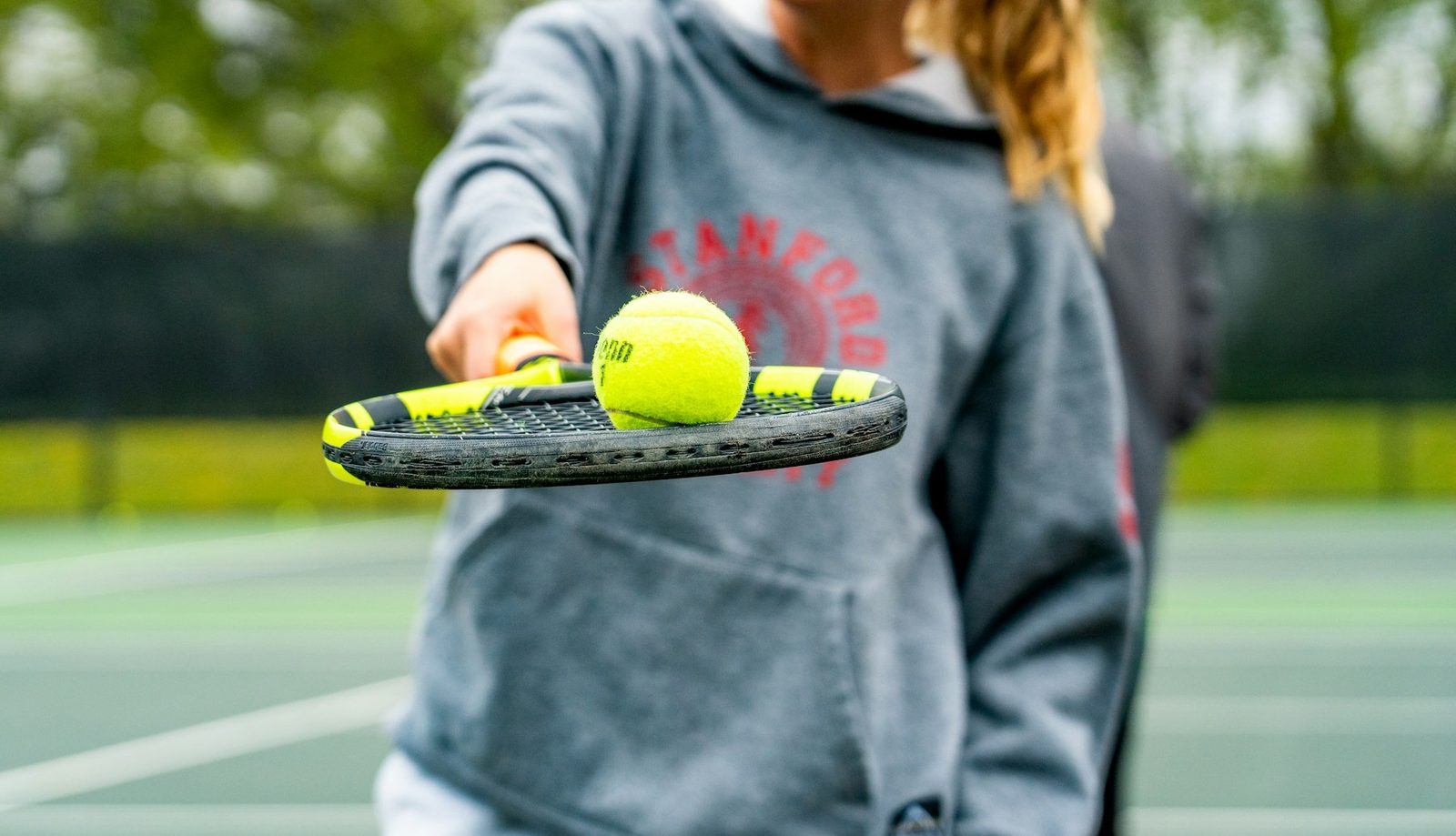 Player holding a racquet and two tennis balls before serving