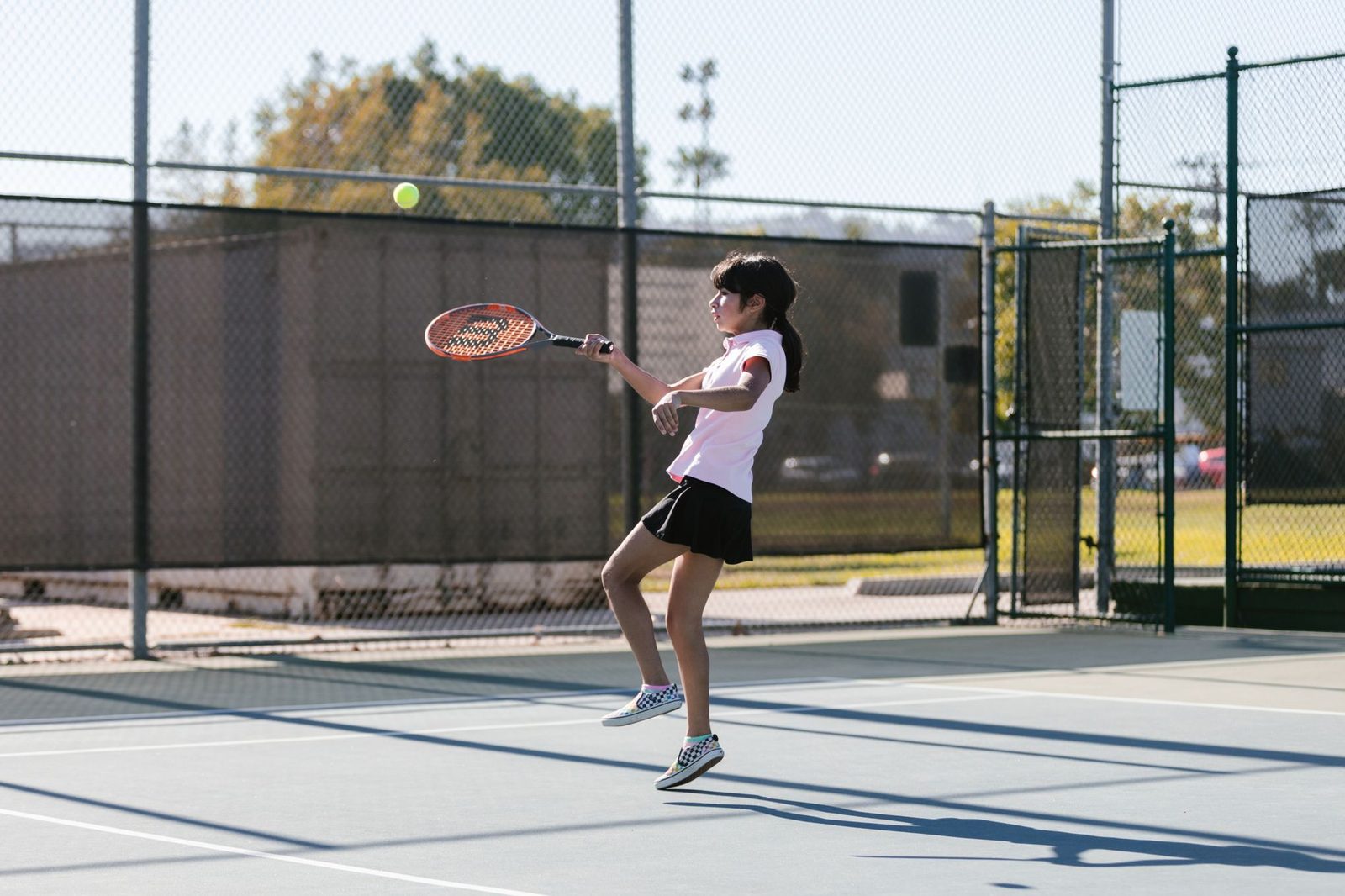 Young girl practising her swing on an outdoor tennis court