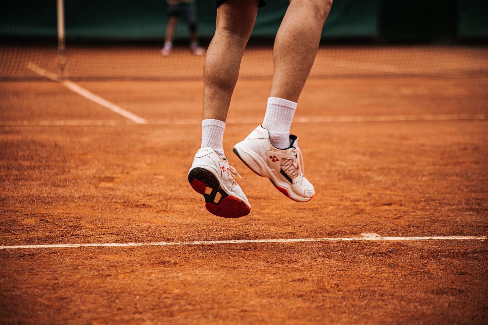 Low angle view of a tennis player jumping on a clay court