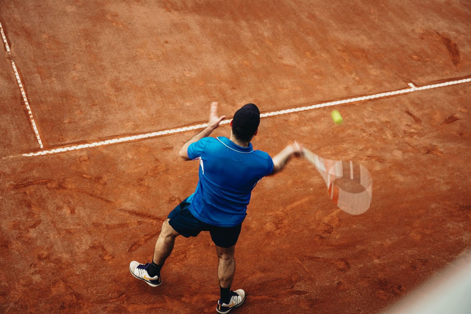 Aerial view of a player serving during a match on a clay court