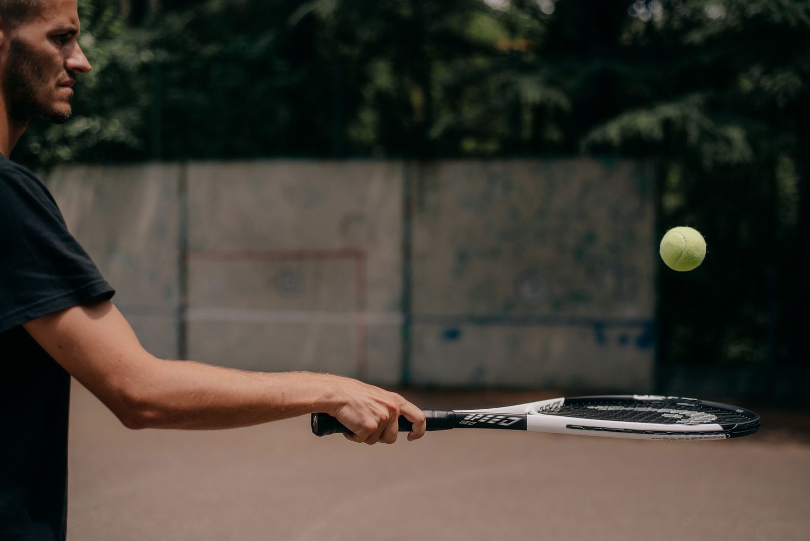 Side view of a player practising his serve outdoors