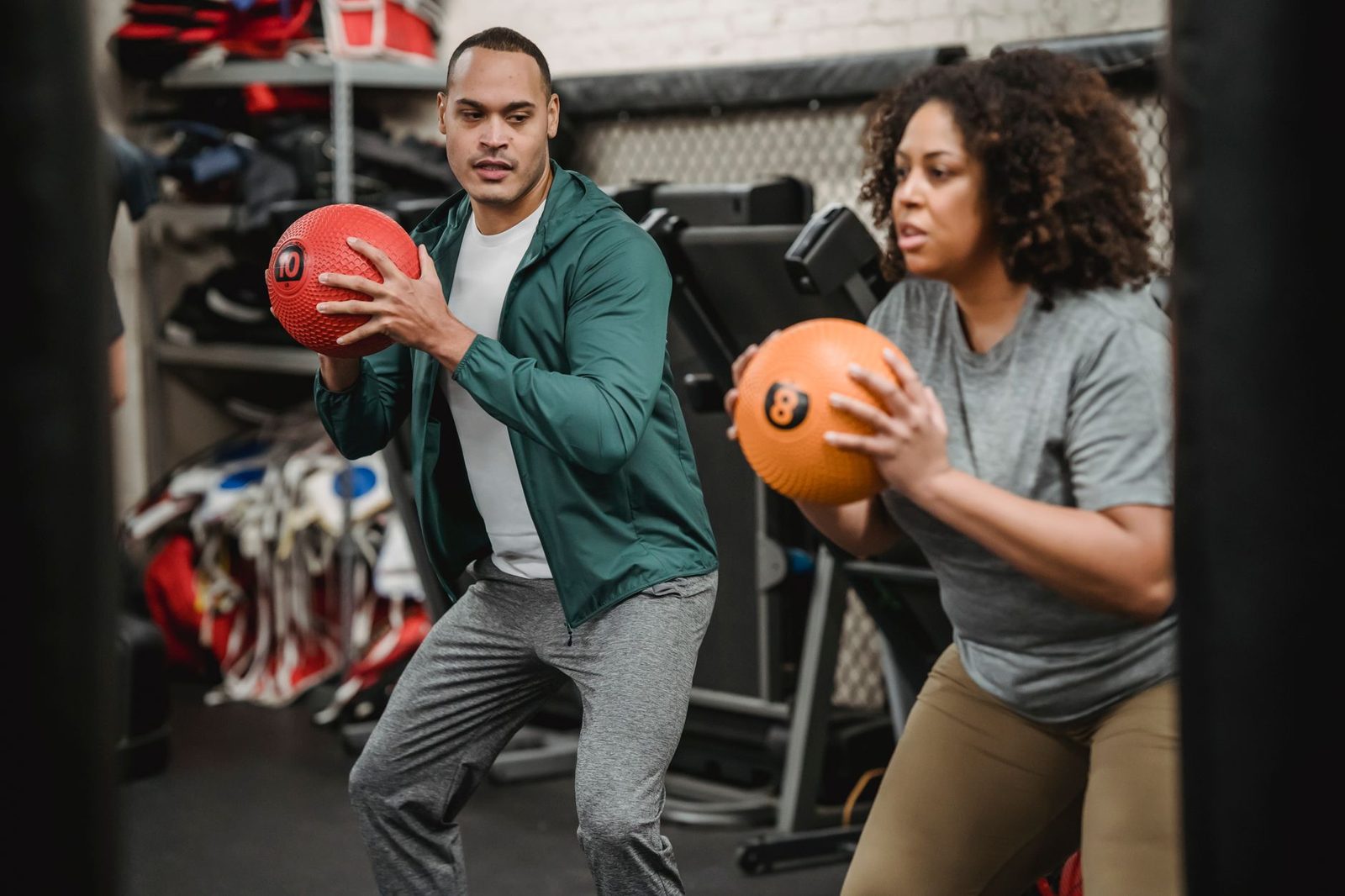 Trainer supervising a medicine ball exercise in the gym