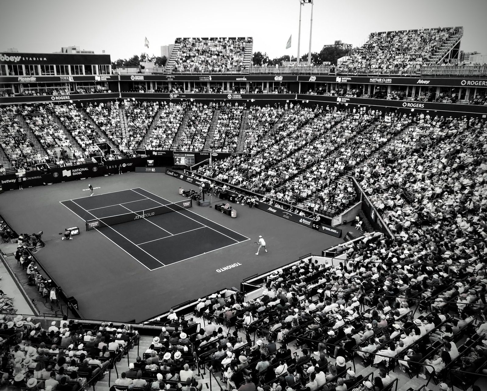 Black and white photograph of a tennis match in an outdoor stadium