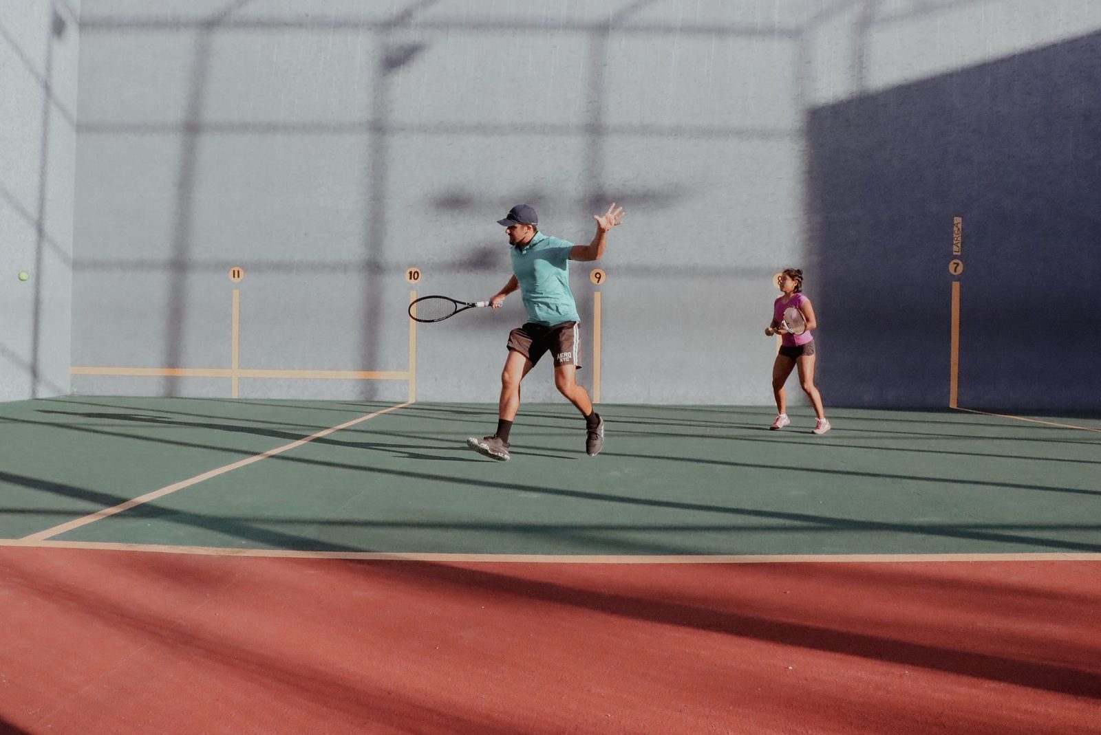 A man and woman in action during an outdoor mixed doubles tennis match