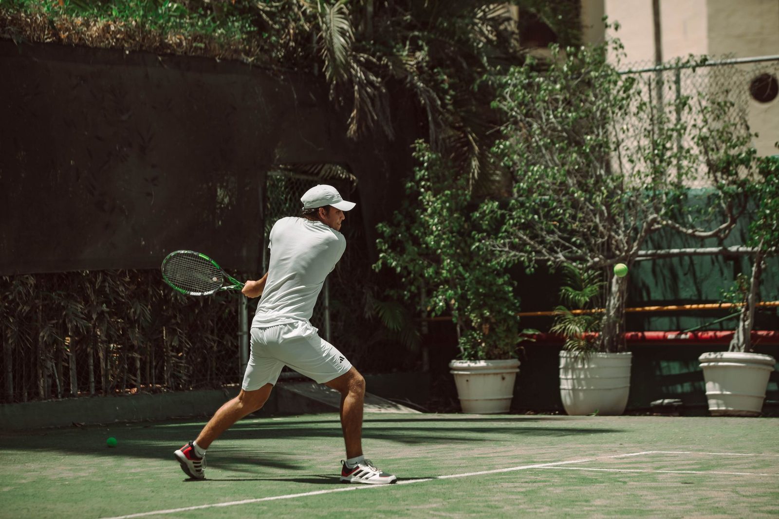 A male tennis player swinging a racquet on a sunlit outdoor court