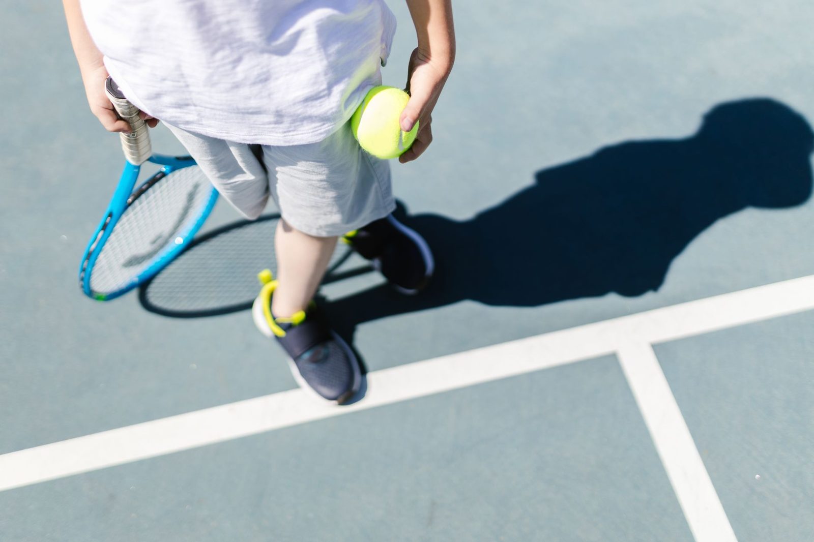 A child holding a tennis racquet and ball on an outdoor court