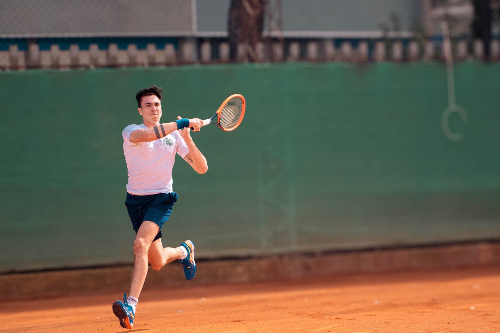 A male tennis player in motion on a clay court during a match