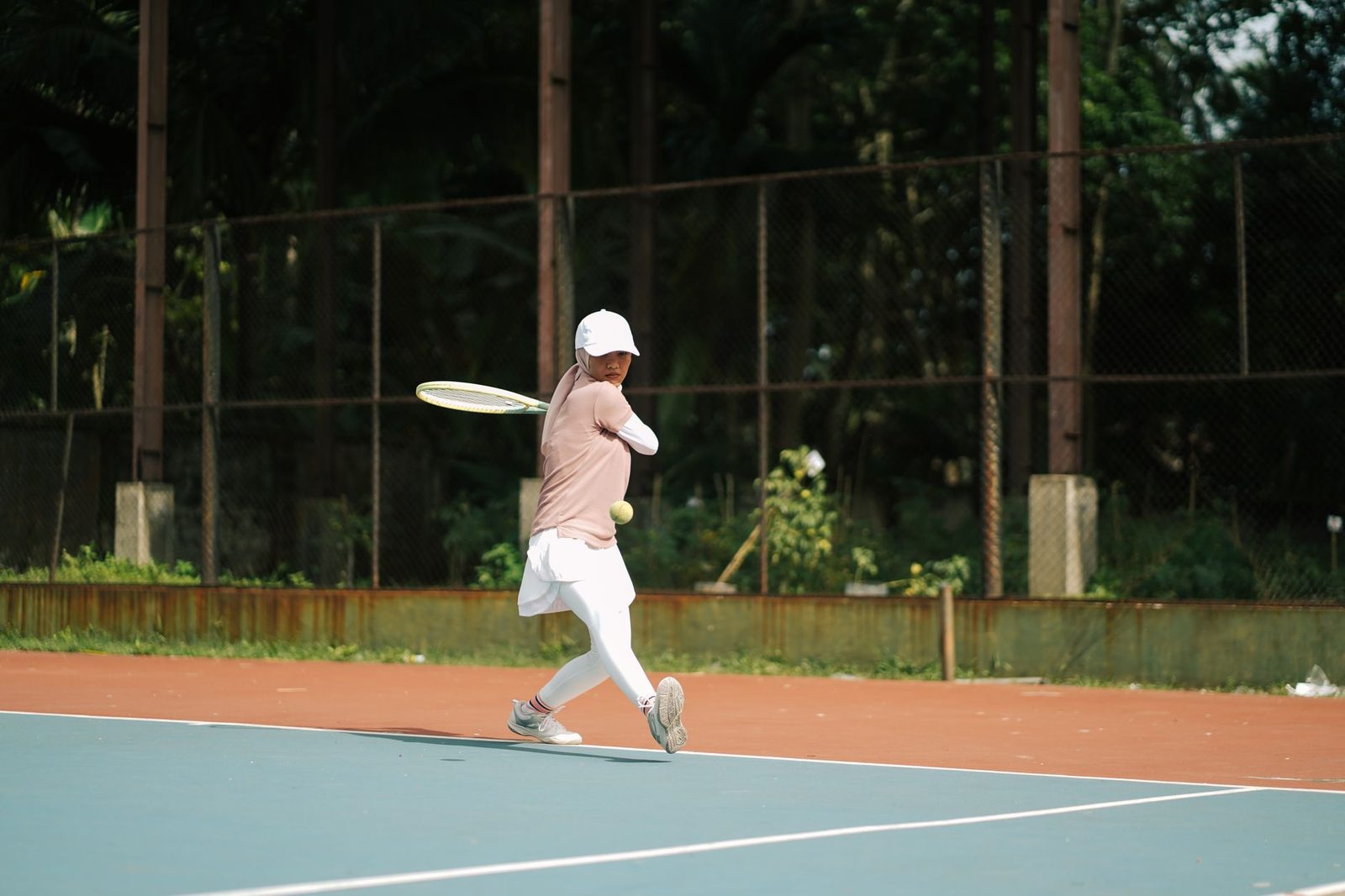 A tennis player executing a powerful backhand swing outdoors