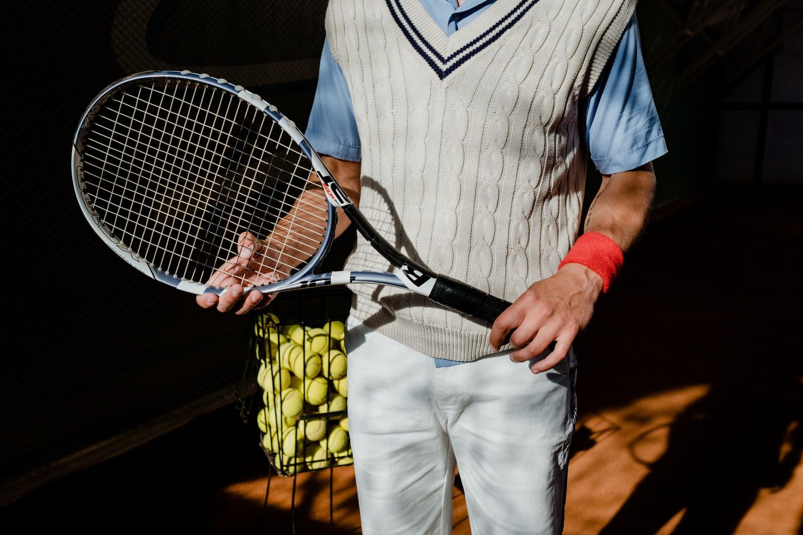 Tennis player holding a racquet and balls on court, ready to play