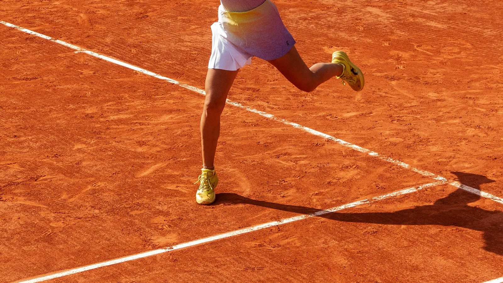 A tennis player running forward on a clay court