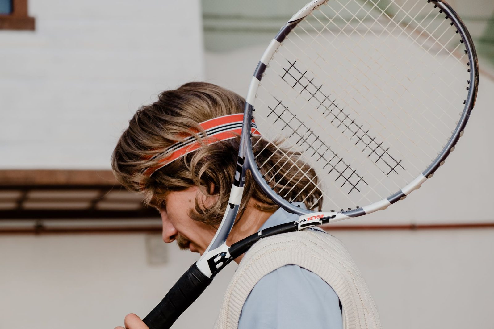 A tennis player resting a racquet on their shoulder outdoors