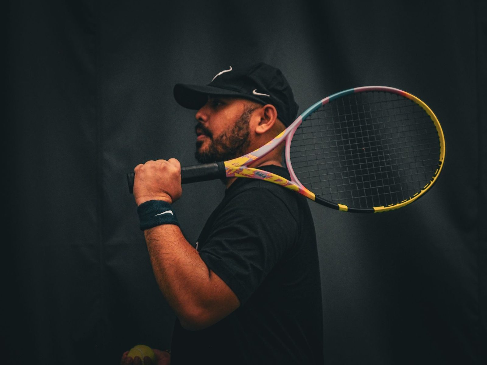 Portrait of a tennis player holding a racquet against a dark background