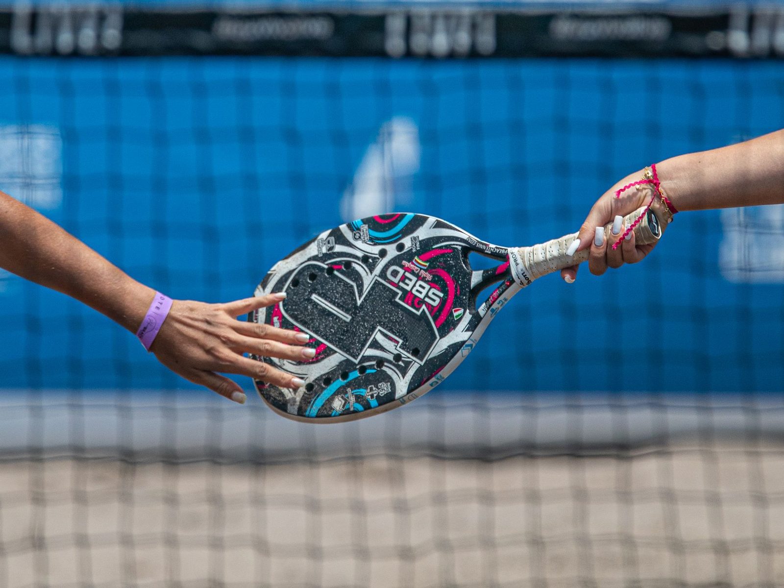 Close-up of two players handling a solid padel racket on an outdoor court